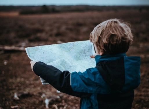 Niño explorando el entorno natural con un mapa durante una actividad educativa